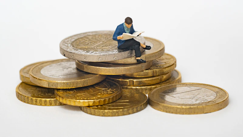 Kleine Figur sitzt lesend auf einem Stapel Euro-Münzen