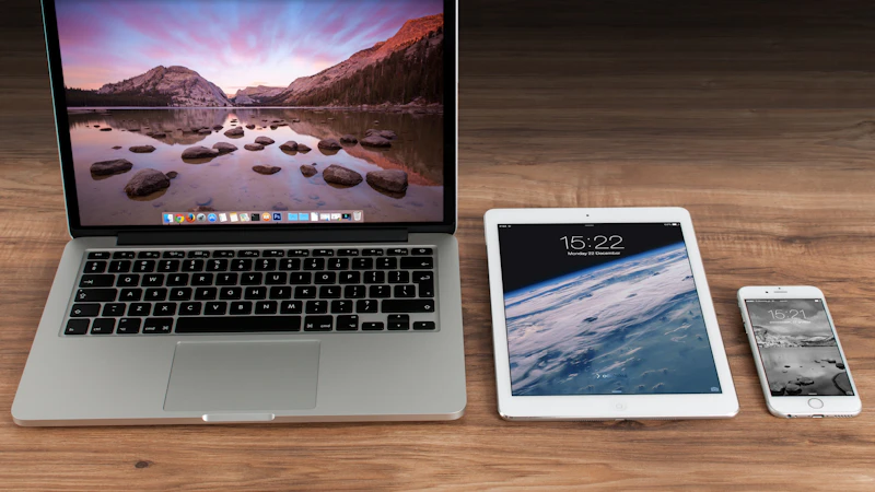 Laptop, Tablet und Smartphone nebeneinander auf einem Holztisch