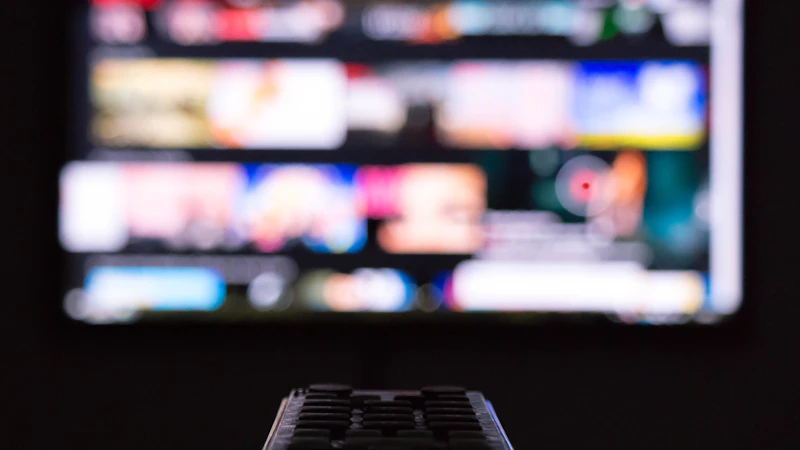 Fernbedienung vor einem Fernseher mit unscharfer Programmübersicht