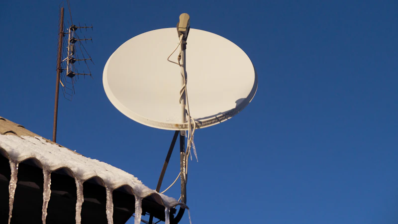 Satellitenschüssel auf einem Dach vor blauem Himmel