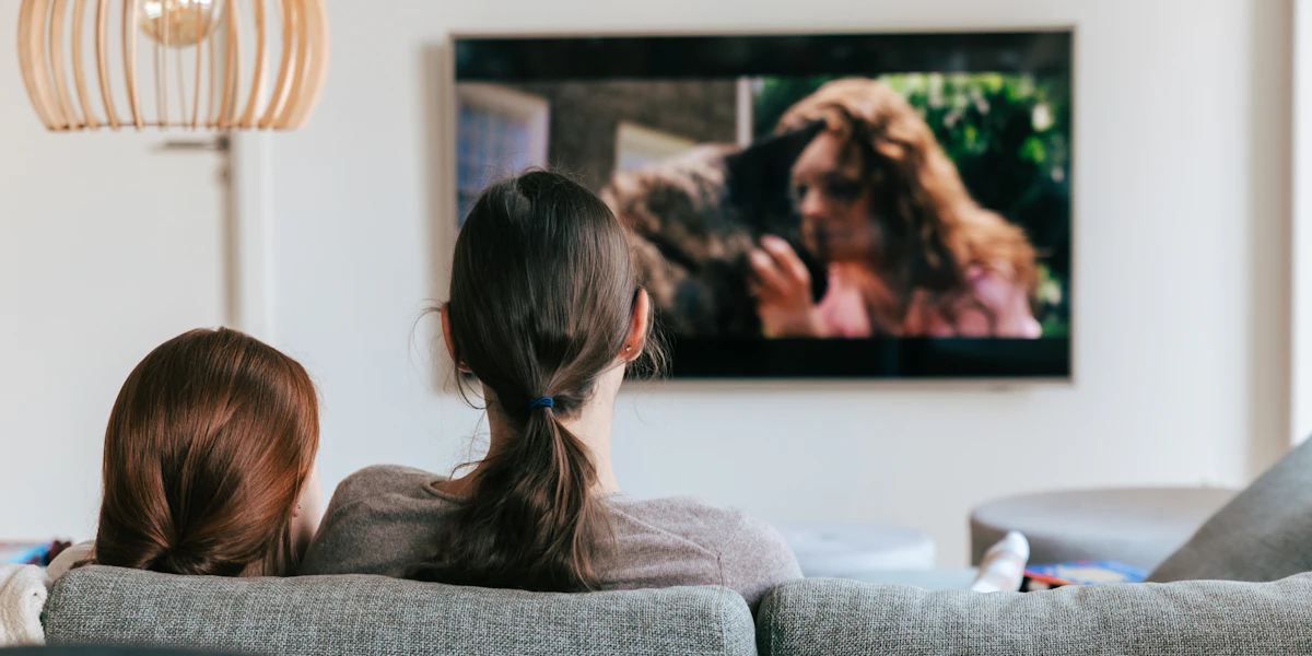 Paar sitzt auf dem Sofa und schaut gemeinsam Fernsehen
